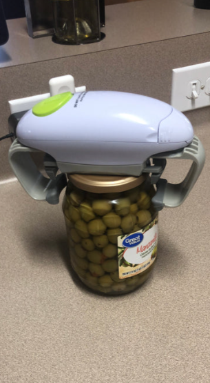 El abre-tarros colocado sobre un bote de aceitunas verdes